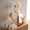 Moderne wandlamp Gastor met drie ronde glazen bollen in amber en helder